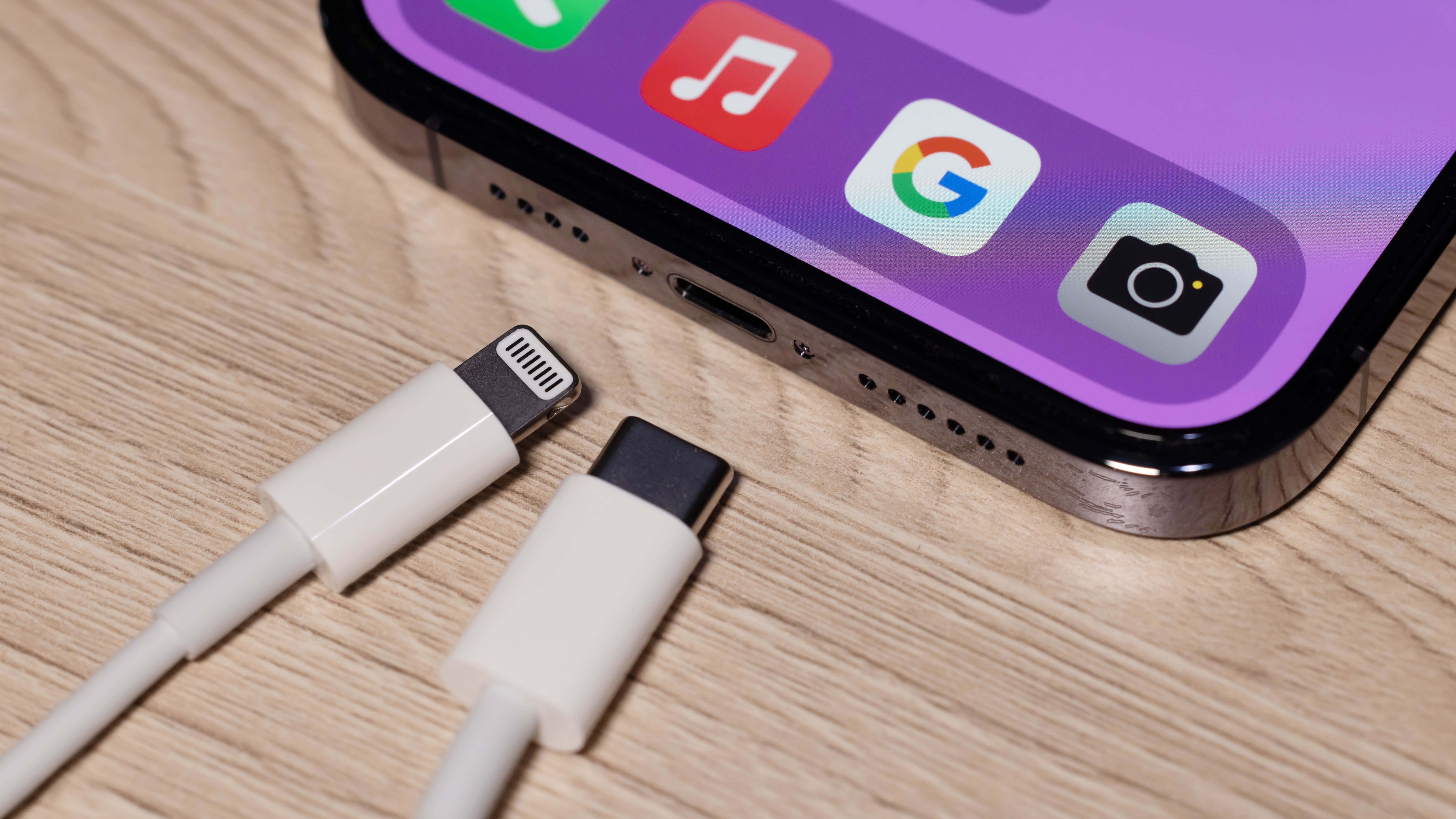 A Lightning charger and USB-C charger next to an iPhone 14